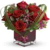 Red roses in glass with imported foliage